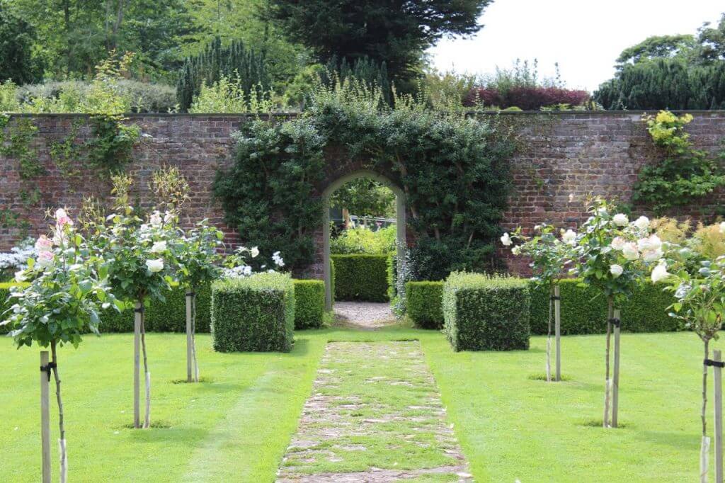 A formal garden gate with clipped hedges and topiary