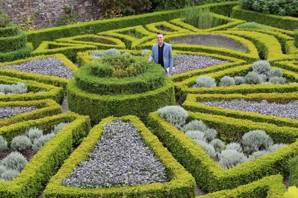 Lee Burkhill Award Winning Garden Designer standing in a topiary maze