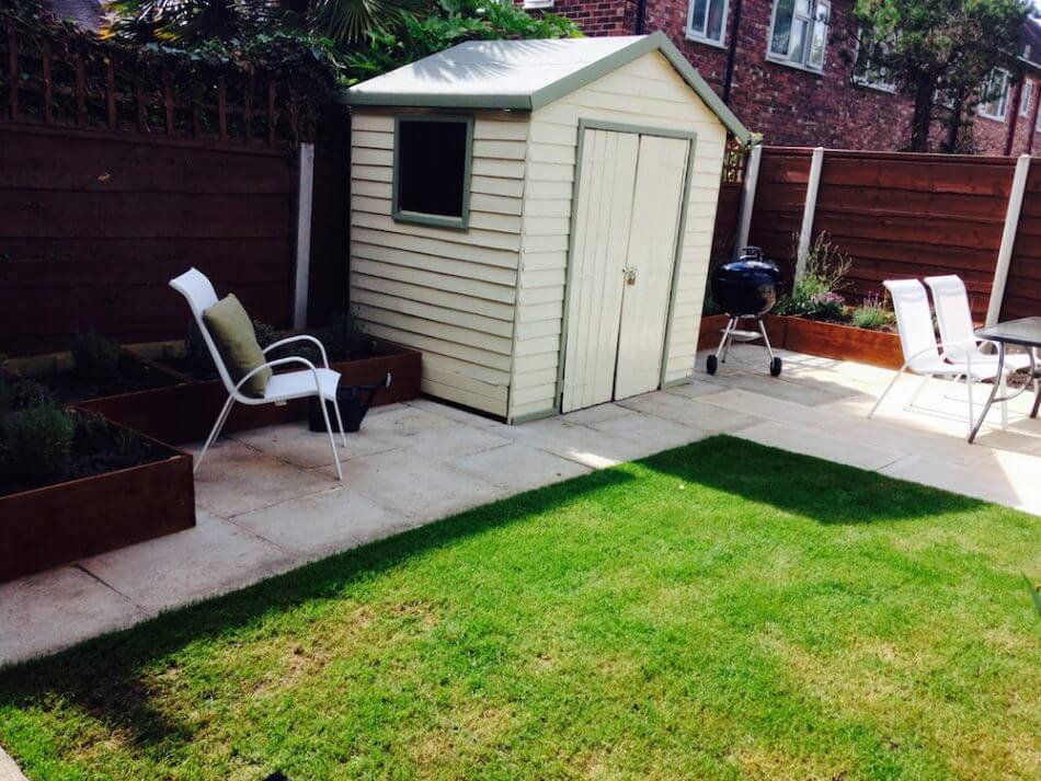 A cream painted shed in a small garden