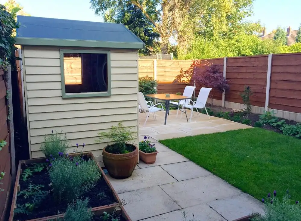 A cream shed newly laid lawn and raised bed garden makeover