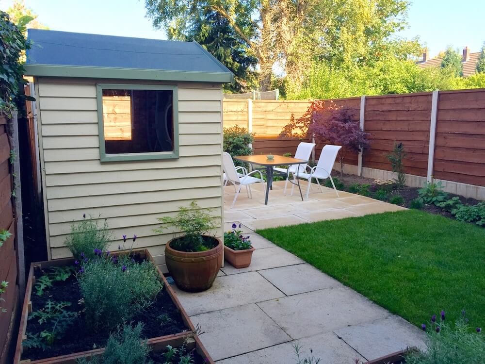 A cream shed newly laid lawn and raised bed garden makeover