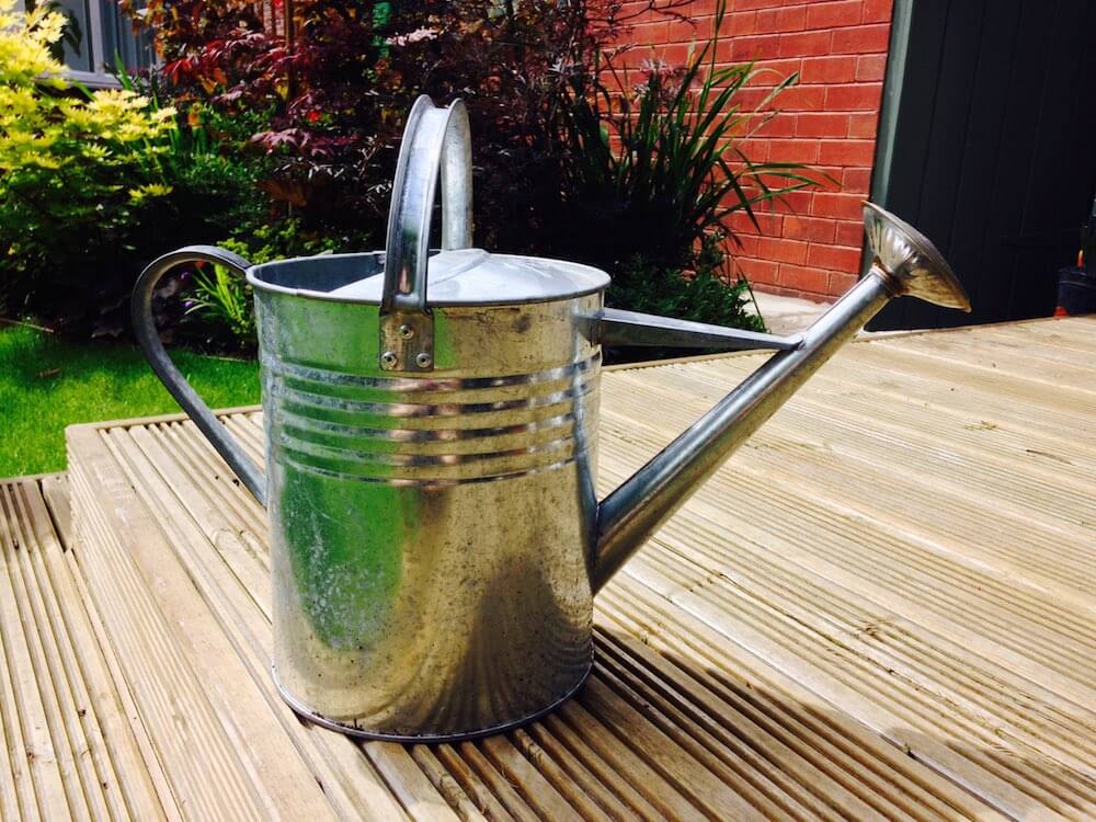 A shiney metal watering can