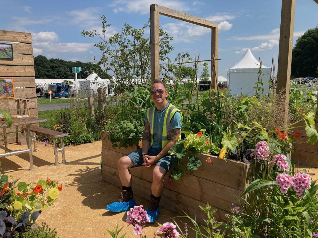 Lee Burkhill sat on a raised bed in a show garden
