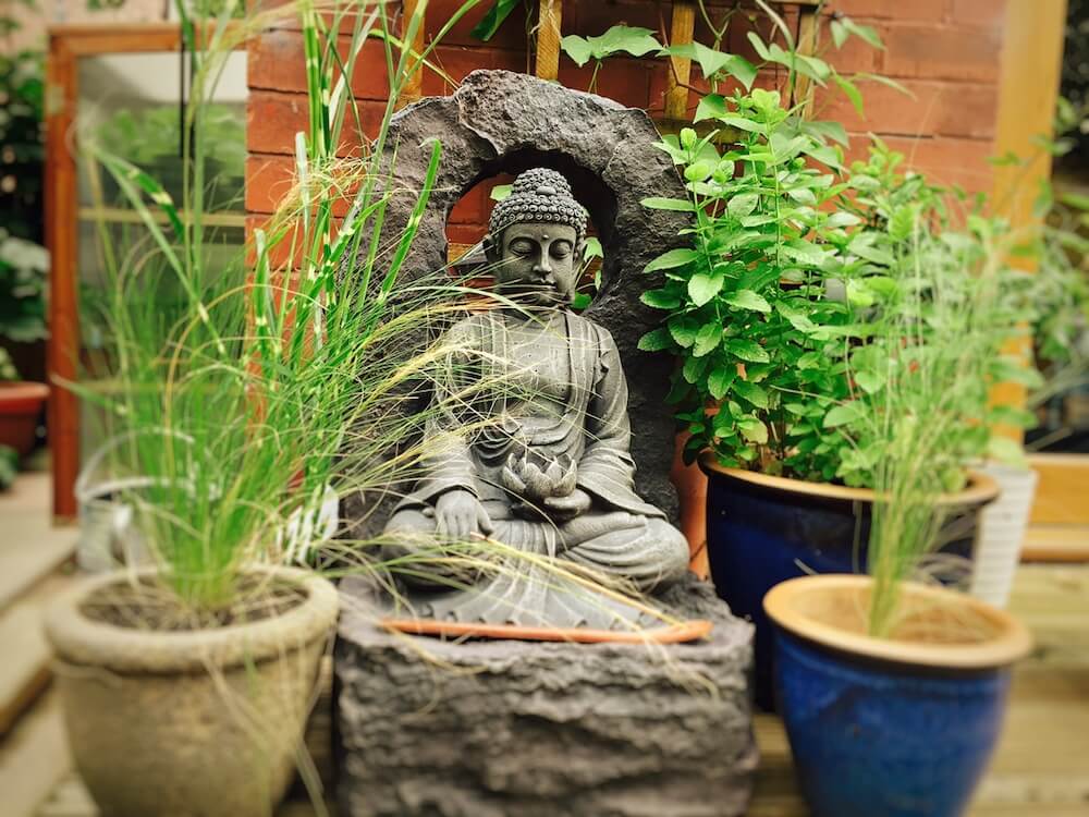 A buddha water feature in a garden