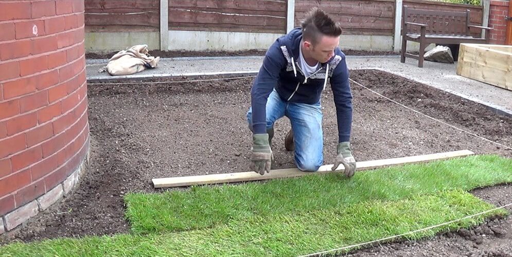 Garden Ninja unrolling turf on a garden makeover