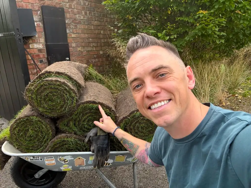 Lee Burkhill pointing at a wheelbarrow of freshly cut rolled turf
