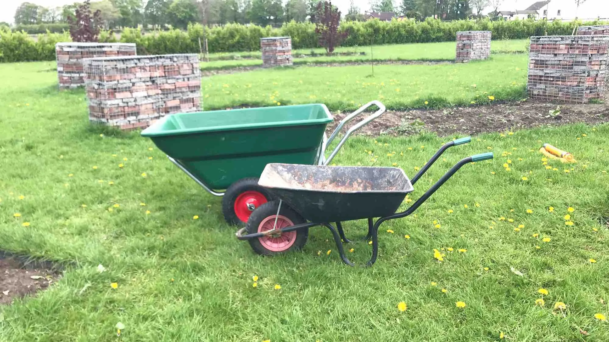 A small and large wheelbarrow side by side