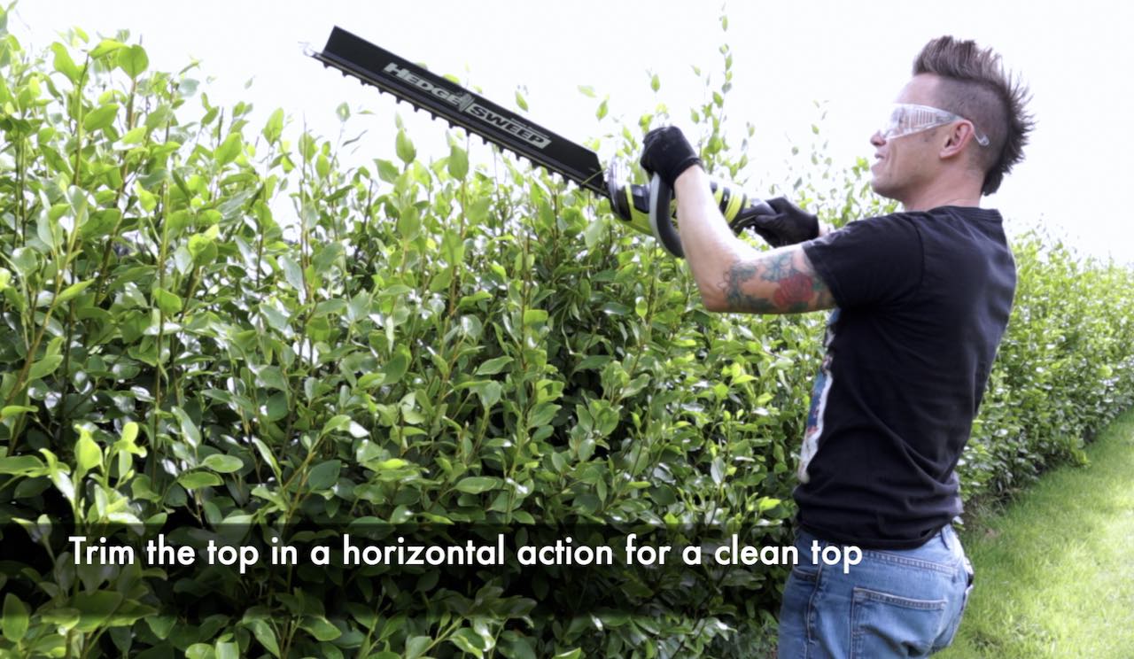 Lee Burkhill using electric hedge cutters on a hedge