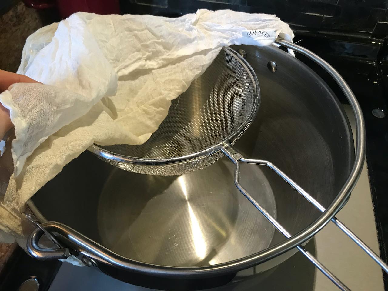Straining cooked medlars through a sieve into a jam pan to make medlar jelly