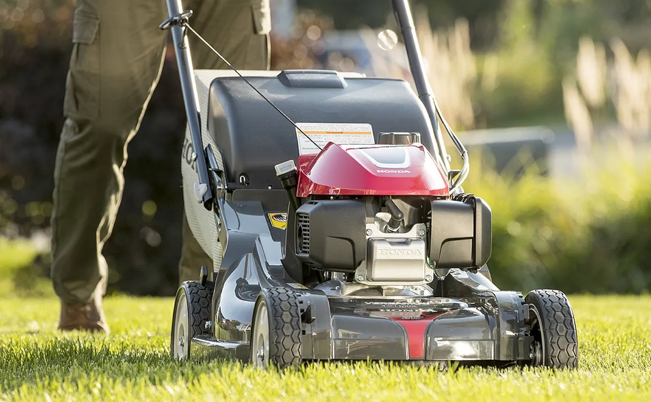 A self-propelled petrol lawn mower being used on a garden lawn