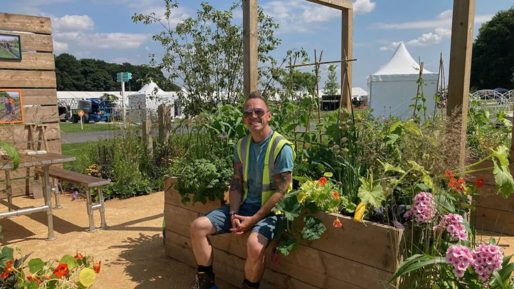 Lee Burkhill sat on a raised bed in a show garden