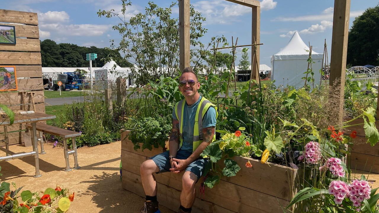 Lee Burkhill sat on a raised bed in a show garden